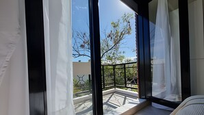 Een balkon met uitzicht op bomen en een gebouw op de achtergrond.
