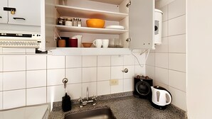 Een keuken met witte kastjes, een granieten aanrecht, een spoelbak en een waterkoker.