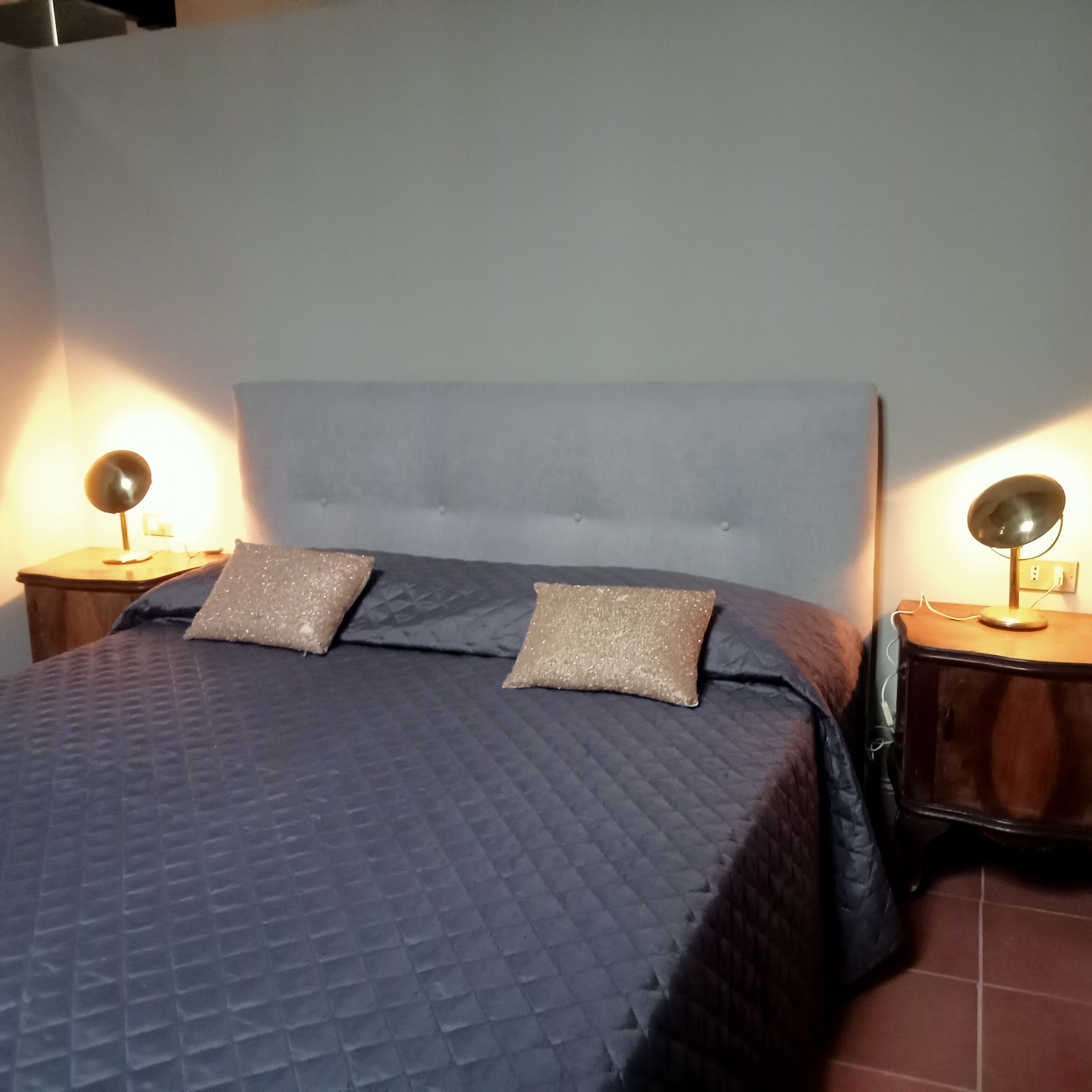 A bed with a quilted cover, two decorative pillows, and two bedside lamps on wooden nightstands.