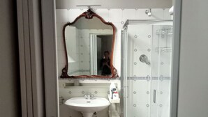 A bathroom with a white sink, a mirror, and a shower. - Palace of Alboin (Pavia)