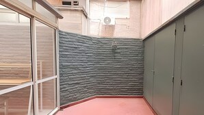 A room with a stone-textured wall, a red floor, and a window with blinds. - Hornera Roca - Amplio y Cómodo, Pleno Microcentro (Rosario)