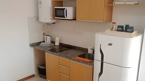 A compact kitchen with a microwave, kettle, and a small refrigerator. - Hornera Lagos - Modern, Spacious & Bright (Rosario)