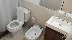 A bathroom with a toilet, bidet, sink, and mirror. - Hornera Lagos - Modern, Spacious & Bright (Rosario)