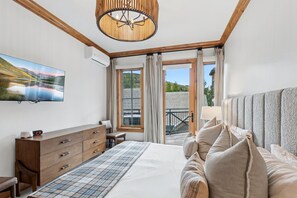 A bedroom with a bed, a dresser, a TV, and a balcony with curtains. - Modern Village Condo by InvitedHome | Pool, Hot Tub, Ski-in/Out, Breakfast (Beaver Creek)
