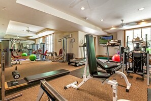 Un gimnasio con máquinas de cardio, equipo de levantamiento de pesas y pelotas de ejercicio.