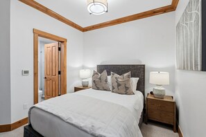 Una camera da letto con un letto, due comodini con lampade, una porta in legno e un'opera d'arte appesa al muro.