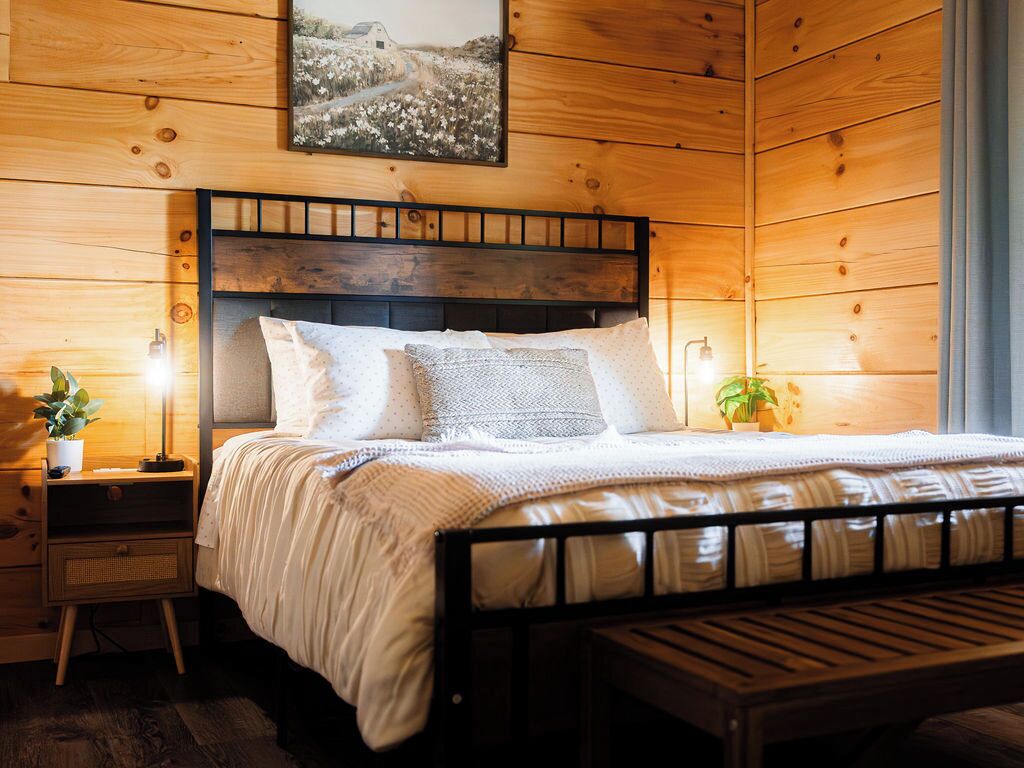 Un dormitorio con paneles de madera, una cama, mesitas de noche y una mesilla.