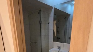 Ein Badezimmer mit Dusche, Waschbecken und Spiegel.