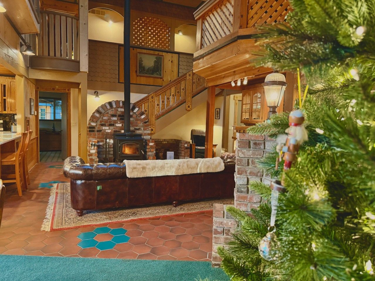 A cozy interior with a fireplace, wooden staircase, and a Christmas tree.