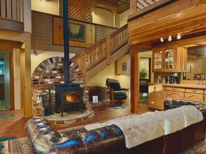 Ein gemütliches Wohnzimmer mit Kamin, einer Treppe und einer Küchenzeile.