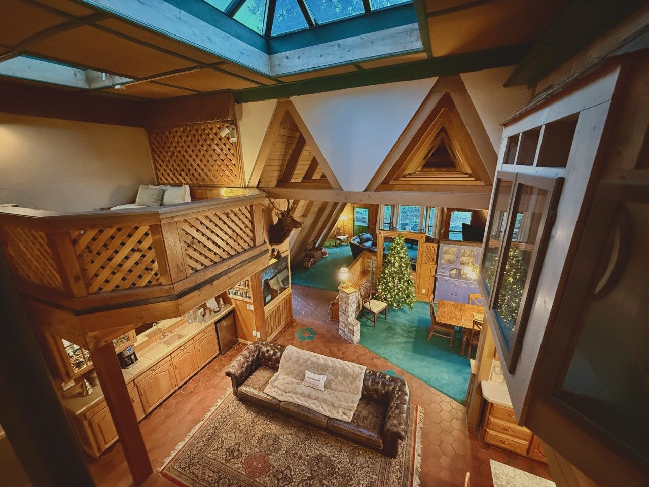 A cozy interior with a loft-style bedroom, a dining area, and a small Christmas tree.