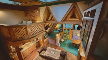A cozy interior with a loft-style bedroom, a dining area, and a small Christmas tree.