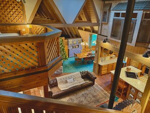 Une cabane en bois à plusieurs niveaux, comprenant une chambre à coucher en mezzanine, un coin repas et une cuisine.