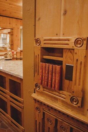 Un meuble en bois doté d’une bibliothèque intégrée contenant plusieurs livres rouges.