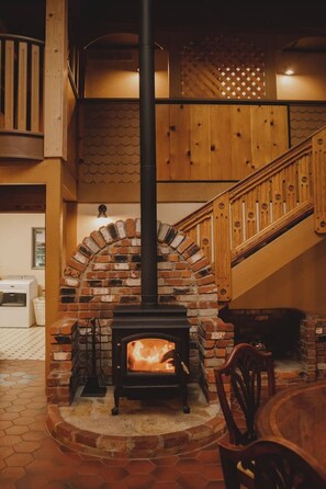 Ein Kamin mit Backsteinbogen, eine Holztreppe und ein Essbereich mit Tisch und Stühlen.