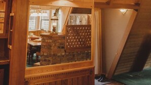 Interior em madeira com um chifre de veado fixado no teto, vigas de madeira e uma lareira de pedra.