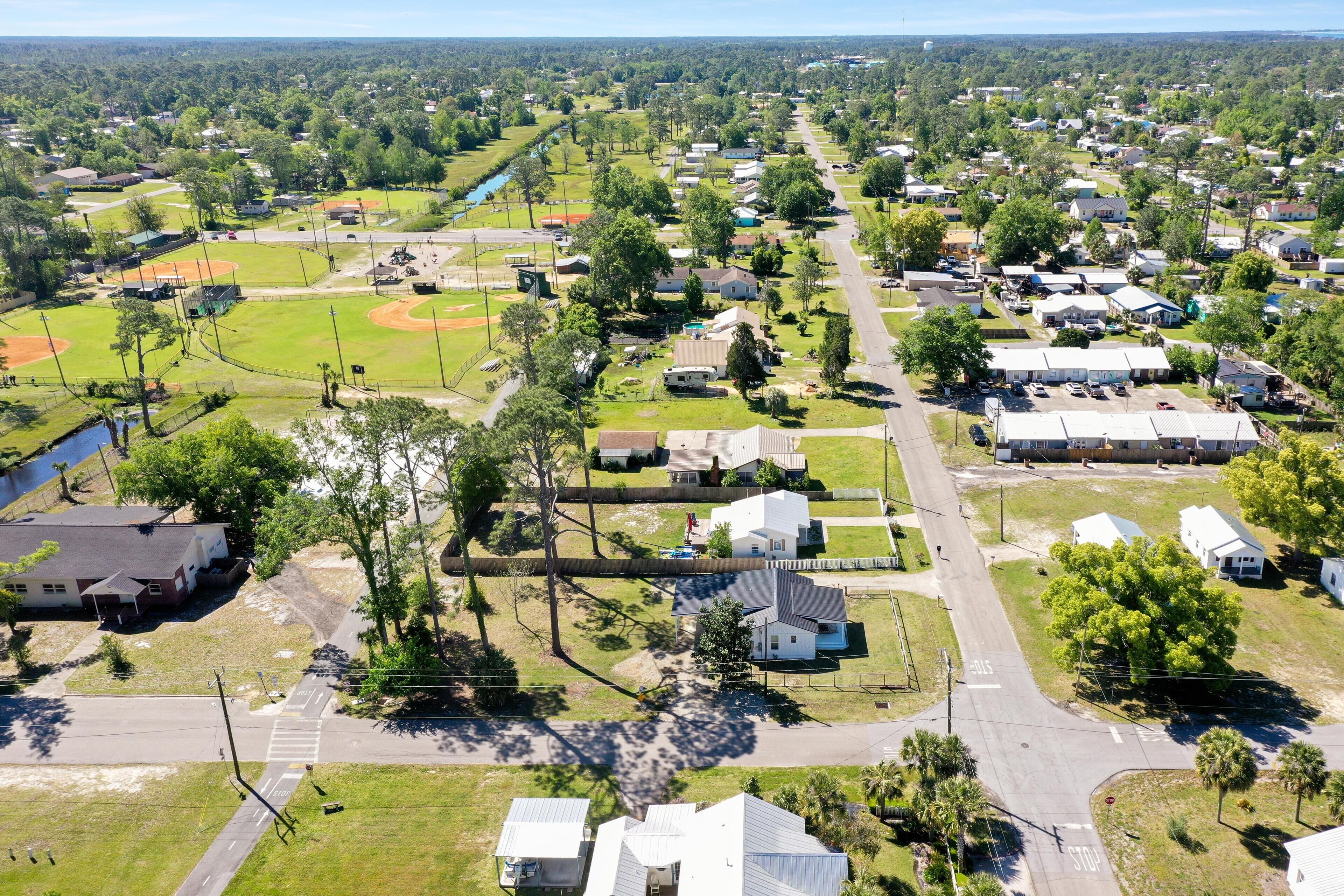 An aerial view of a residential area with houses, a baseball field, and a road.