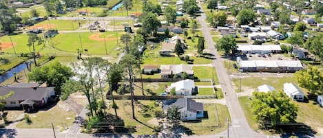 An aerial view of a residential area with houses, a baseball field, and a road.