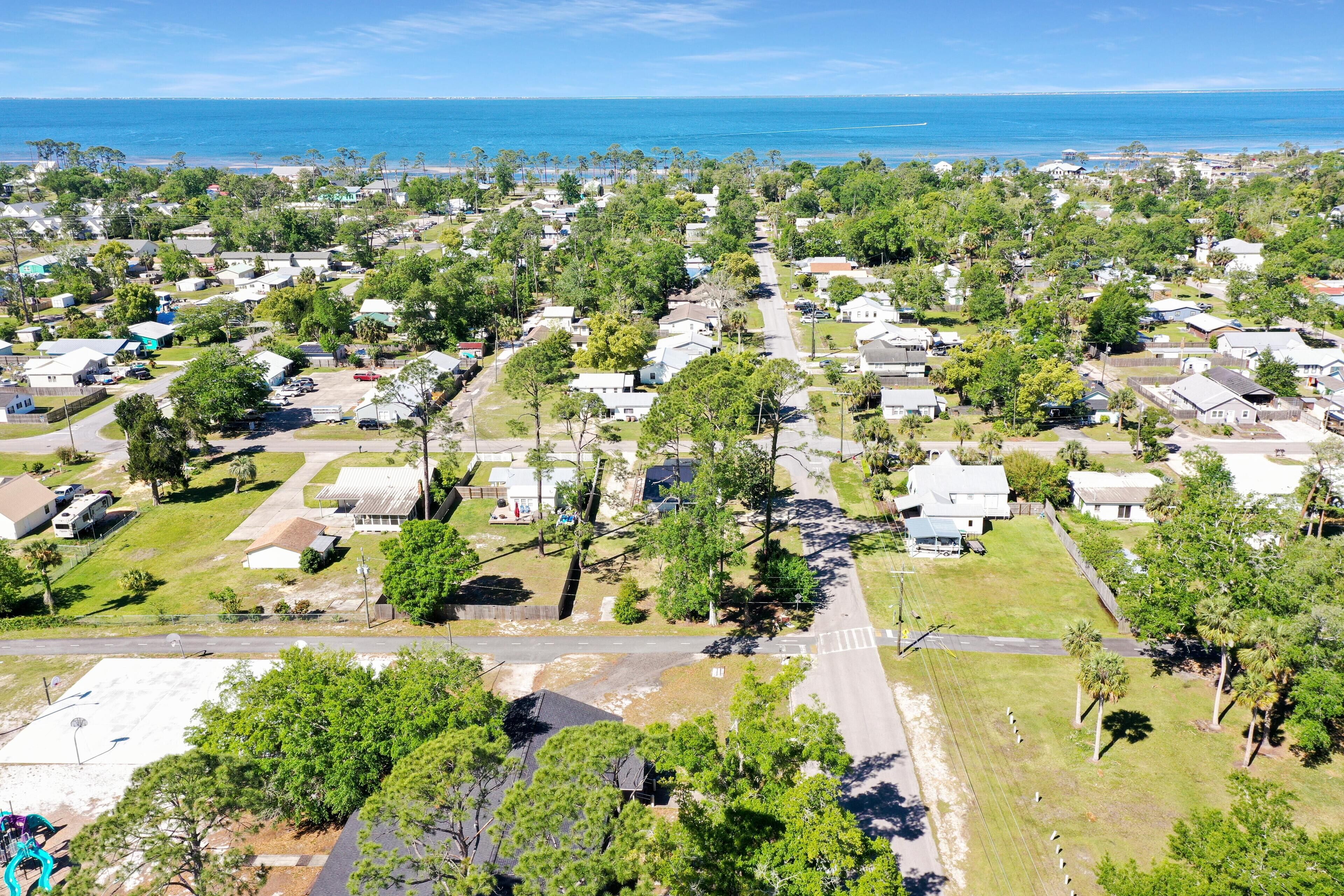 An aerial view of a residential area with houses, roads, and a beach in the background.