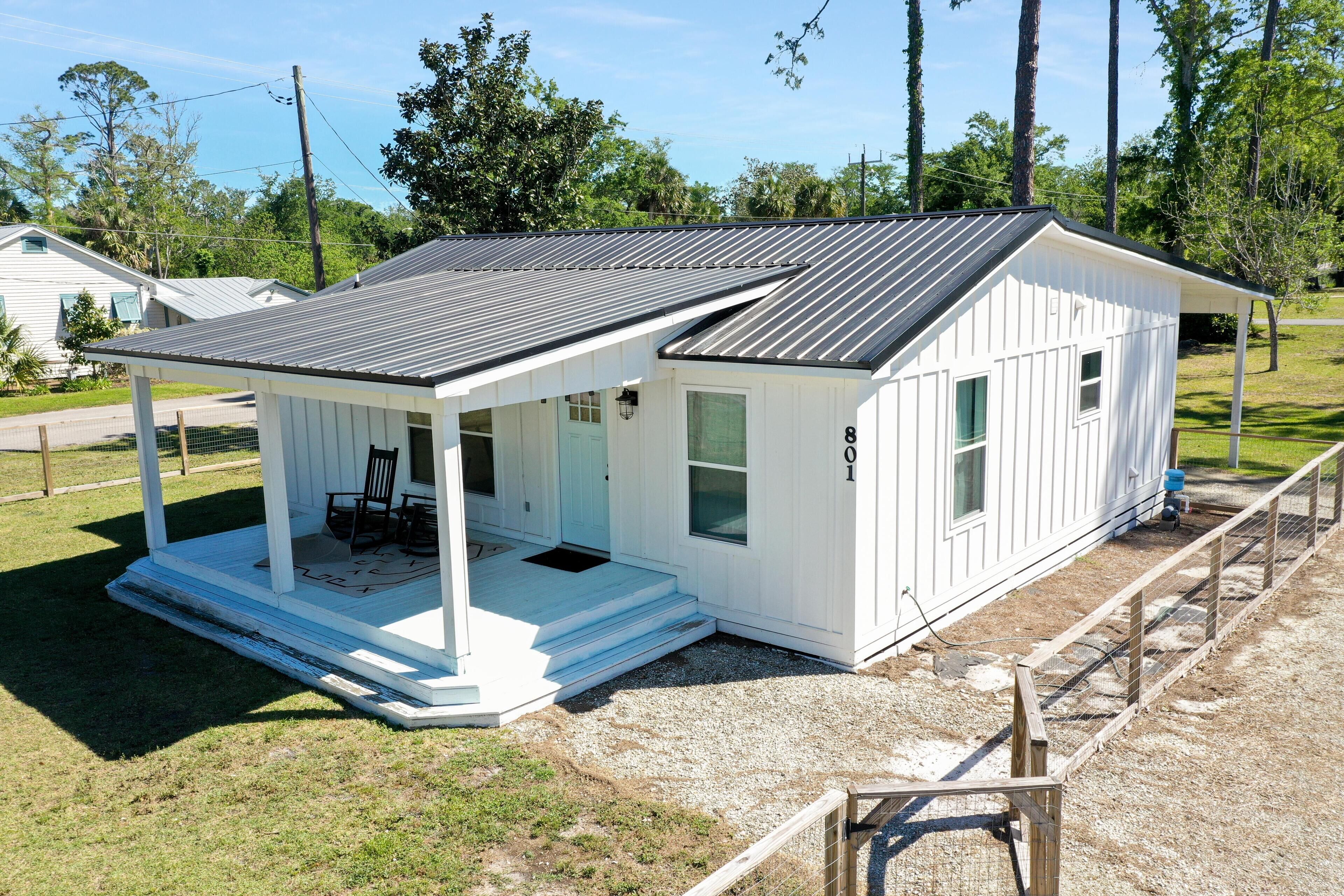 A small, single-story white building with a covered porch and a metal roof.