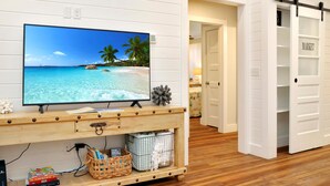 Una stanza con una TV su un mobile in legno, una porta bianca e una parete bianca.
