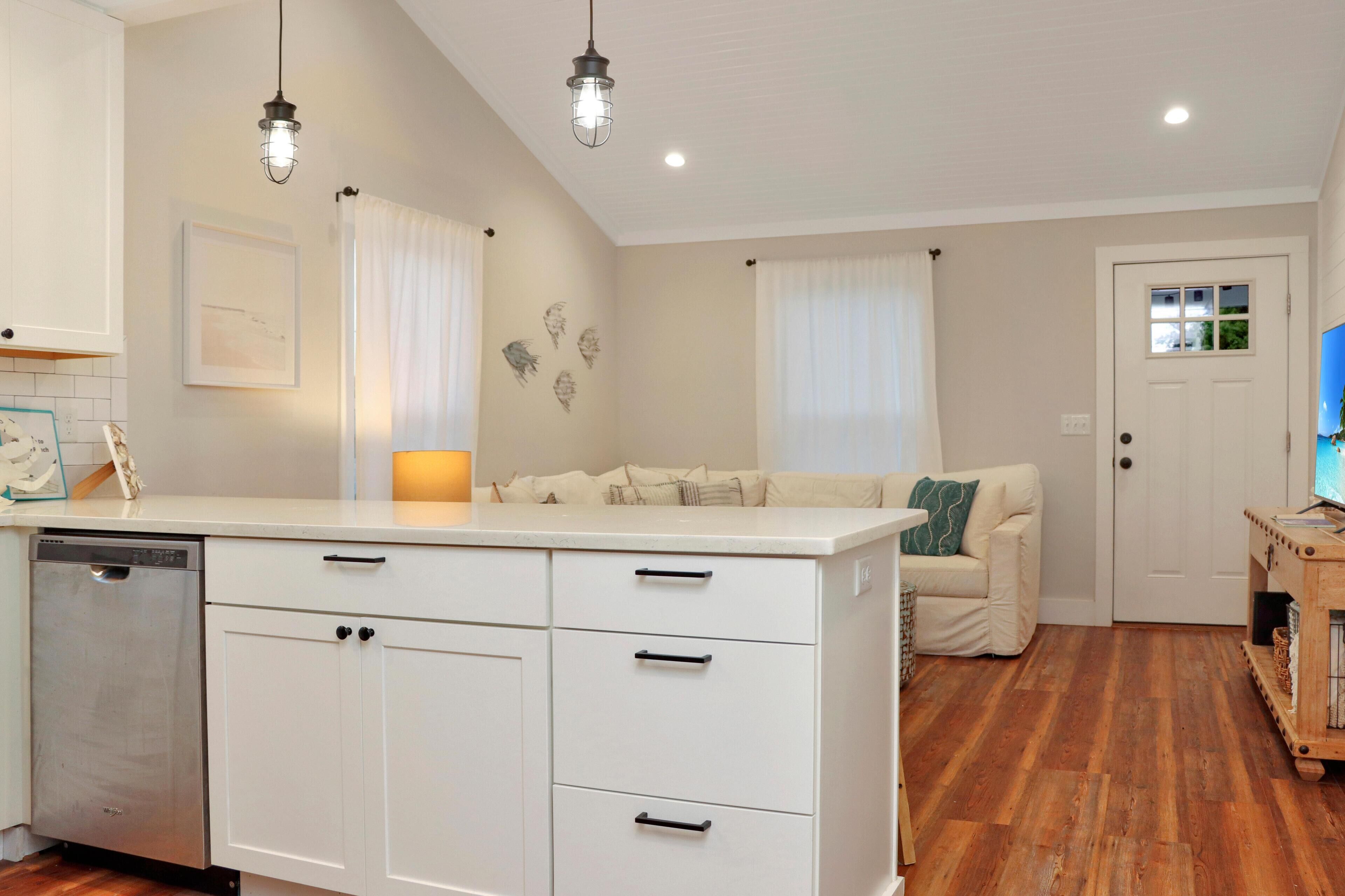 A compact kitchen with white cabinets, a dishwasher, and pendant lighting.