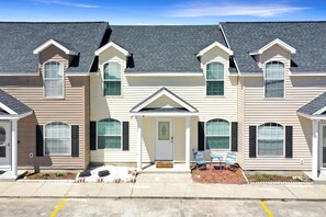 A row of townhouses with a central entrance, a small porch, and a parking area in front. - The Palms 2B (Port St. Joe)