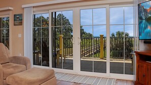 A living room with a sliding glass door leading to a balcony. - Club at Cape San Blas 1C - Sandpiper (Port St. Joe)