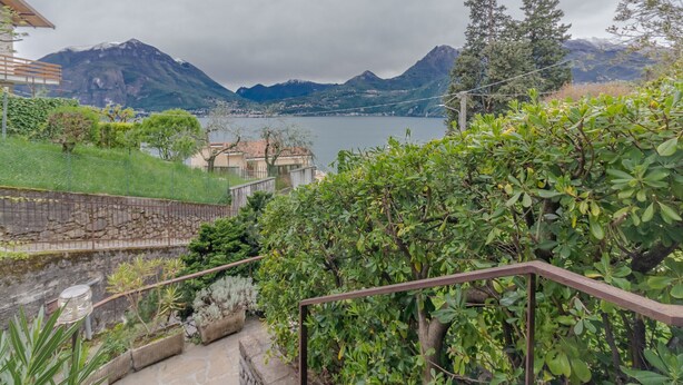 Un paysage pittoresque de montagnes, avec un lac, une végétation luxuriante et un sentier de pierres menant à un bâtiment.