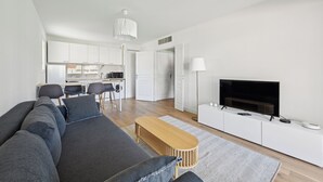 A modern living room with a sofa, TV, and a dining area with chairs and a table. - Appartement Ensoleillé Avec Terrasse à Cannes (Cannes)