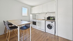 A compact kitchen with white cabinets, a wooden table, and a washing machine. - Appartement Ensoleillé Avec Terrasse à Cannes (Cannes)