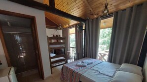 Un dormitorio con una cama, una silla de madera, una mesita y una ventana con cortinas.