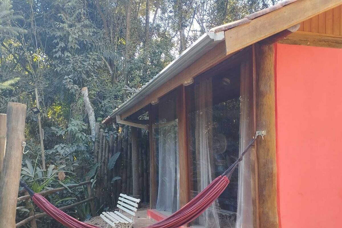A house with a red exterior, a wooden porch, and a hammock.