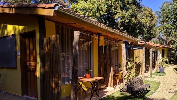Una hilera de edificios amarillos con balcones de madera, un sendero pavimentado y una pequeña zona verde con bancos.