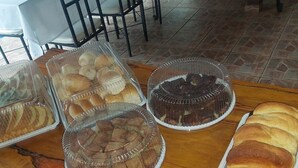 Una mesa con diversas opciones de panadería en recipientes transparentes, como panecillos, pasteles y una tarta.