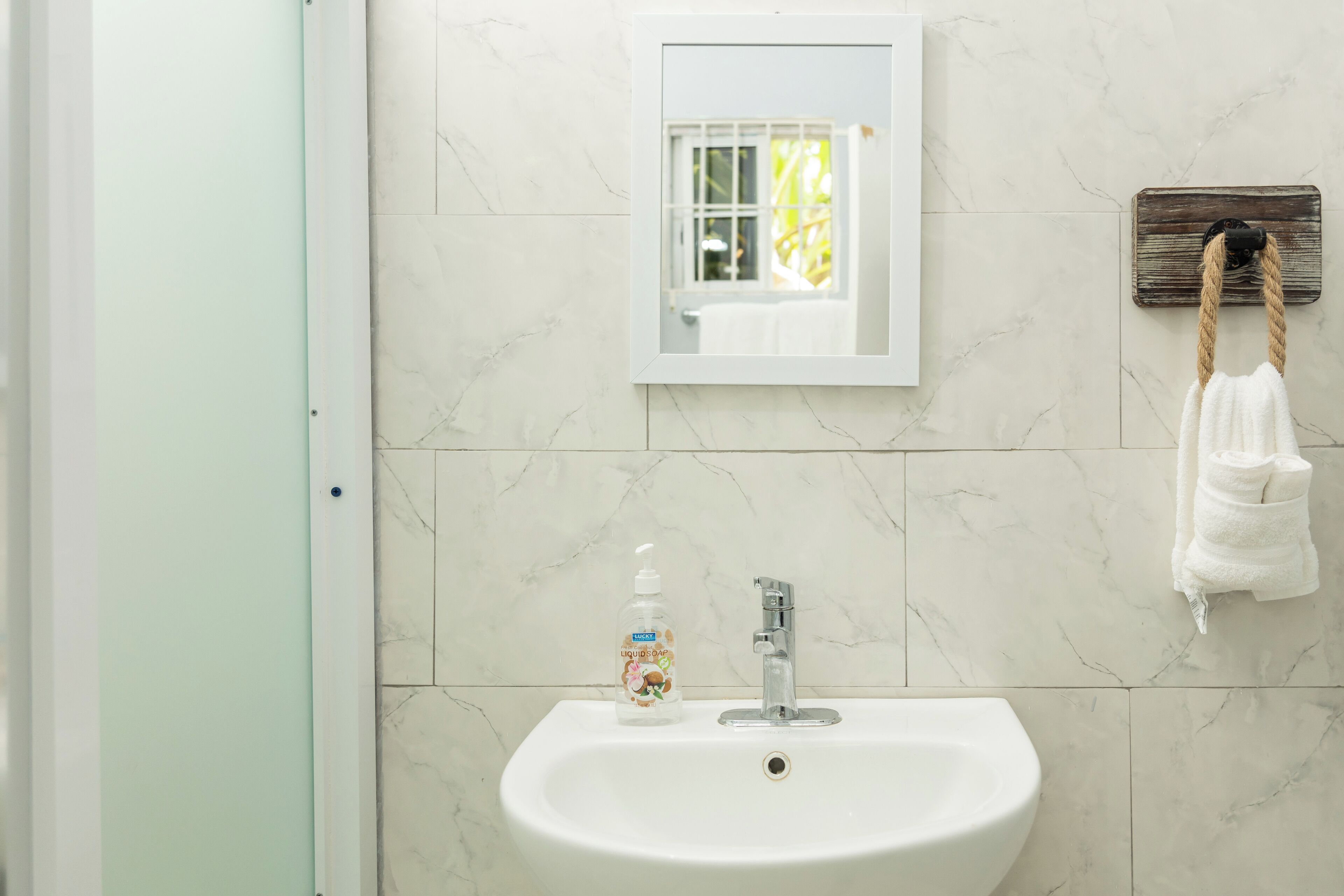 A bathroom with a white sink, a mirror, and a towel rack with a towel.