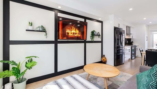 A modern living room with a fireplace, a dining area, and a kitchen. - Rare Find in Best Location, Work/Family Friendly (Calgary)