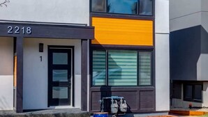 A modern two-story house with a large window, a visible water heater, and a well-maintained lawn. - Pet Friendly 4BDR w/ Main Floor office/Bed (Calgary)