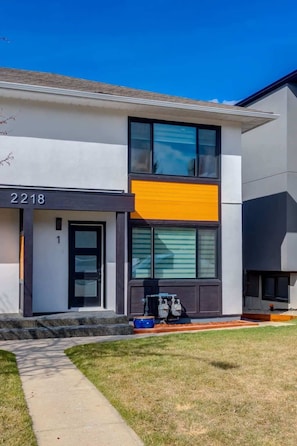 A modern two-story house with a large window, a visible water heater, and a well-maintained lawn. - Pet Friendly 4BDR w/ Main Floor office/Bed (Calgary)