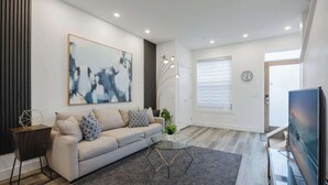 Una sala de estar moderna con sofá, mesa de centro y una obra de arte en la pared.