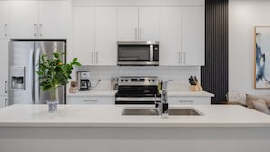 Una cocina moderna con armarios blancos, electrodomésticos de acero inoxidable y una isla central.