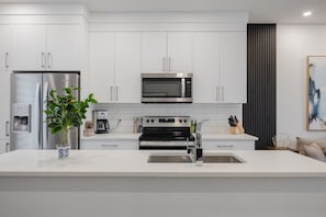 A modern kitchen with white cabinetry, stainless steel appliances, and a central island. - Free Parking, Pet Friendly, 3 BDR, Prime Location (Calgary)