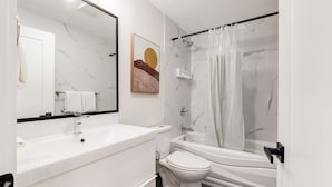 Ein modernes Badezimmer mit Waschbecken, Toilette und Badewanne in Weiß.