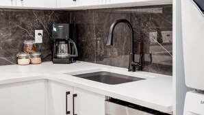 A modern kitchen with a white countertop, black faucet, and stainless steel appliances.