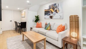 A modern living room with a sofa, coffee table, and a dining area with chairs.