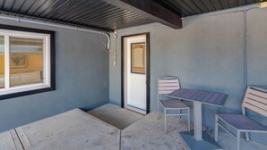 Ein Zimmer mit Fenster, Tür und einem kleinen Tisch mit zwei Stühlen.