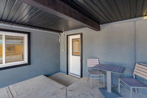 Een kamer met een raam, een deur en een kleine tafel met twee stoelen.