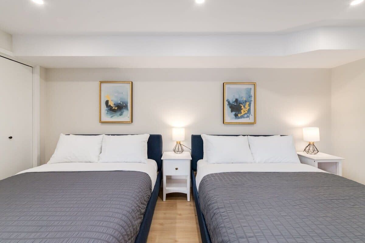 A hotel room with two beds, nightstands, and wall art.