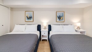 A hotel room with two beds, nightstands, and wall art.