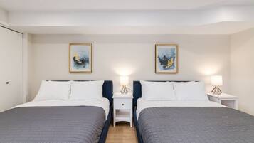 A hotel room with two beds, nightstands, and wall art.